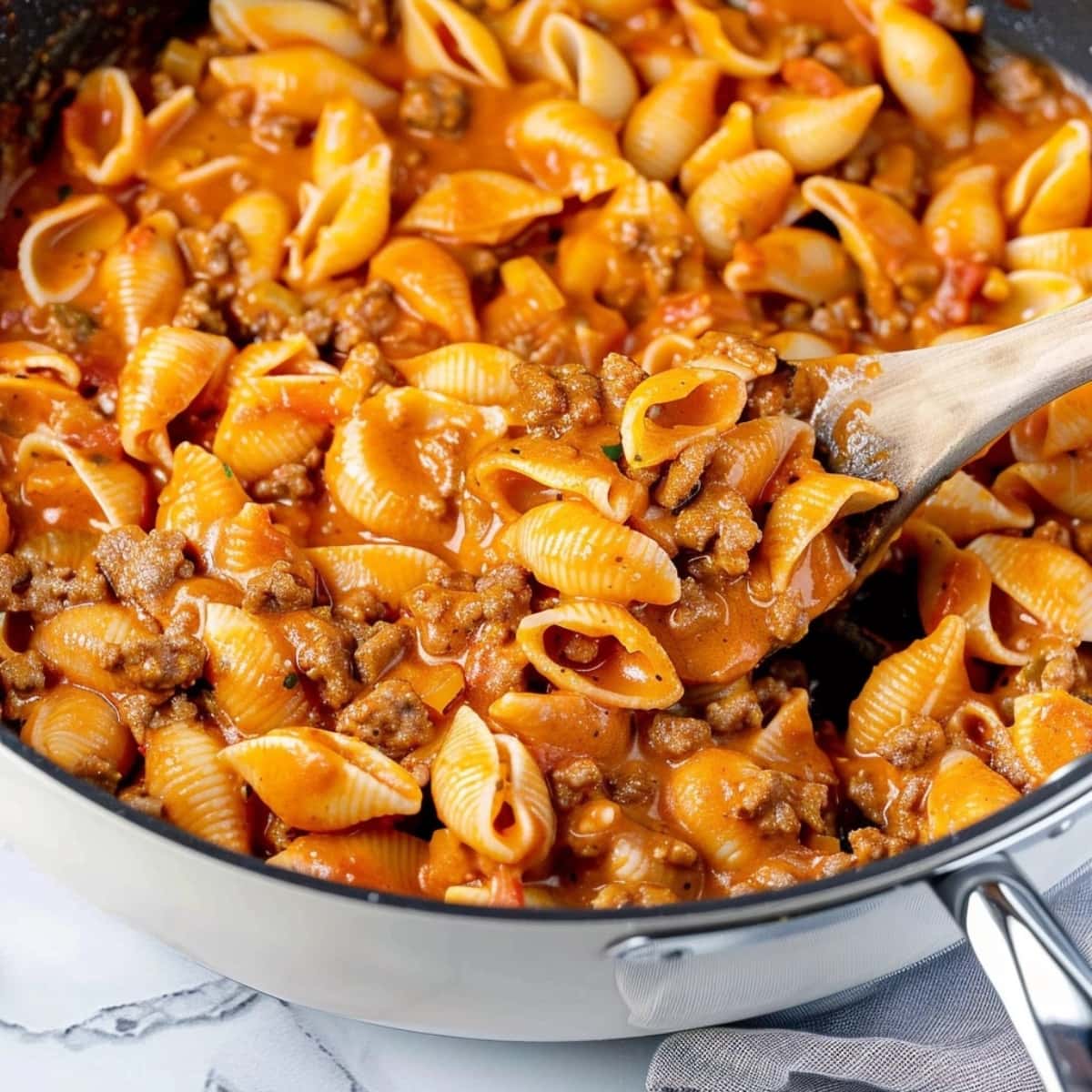 Beef and shells in cheesy tomato sauce tossed in a large skillet.