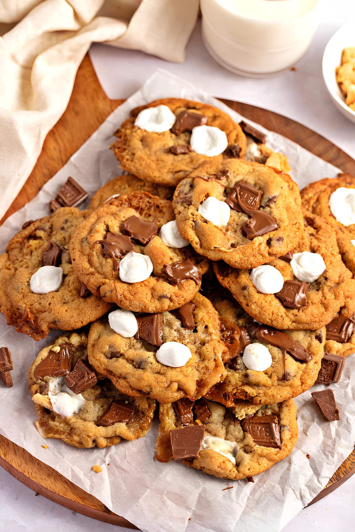 Hershey's Cookies with melted chocolate bars and marshmallows on top served on a wooden board with parchment paper lining.