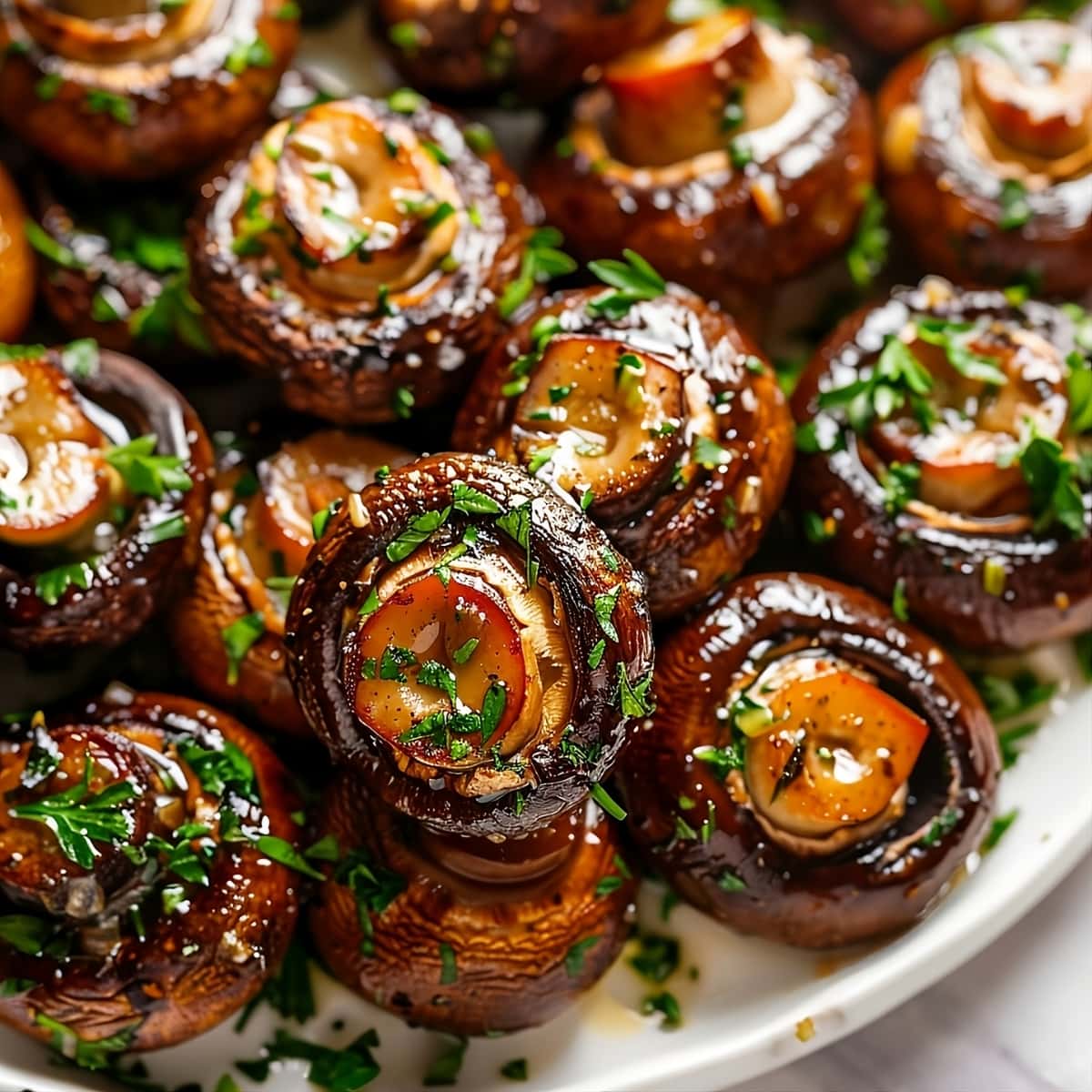 Button mushroom sautéed in garlic and butter seasoned with thyme and pepper served on a white plate