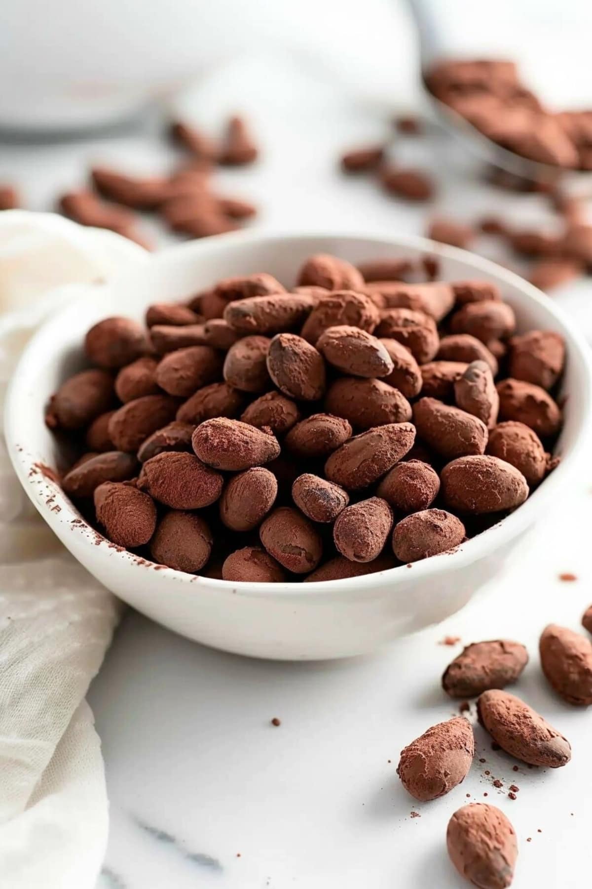 Bunch of chocolate and cocoa coated almonds in a white bowl.