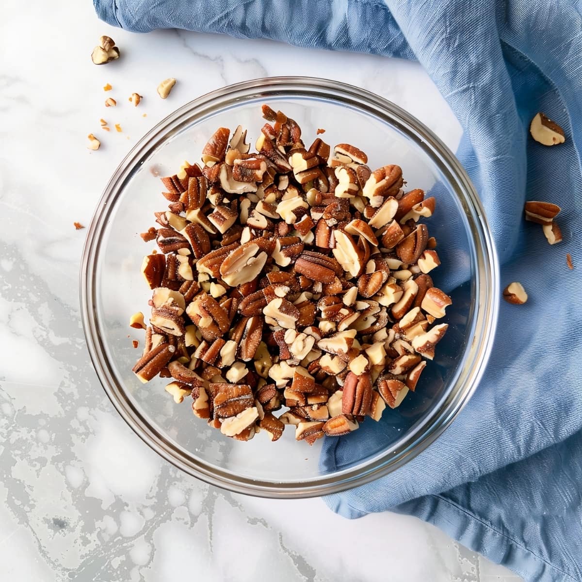 Raw organic chopped nuts in a glass bowl, top view