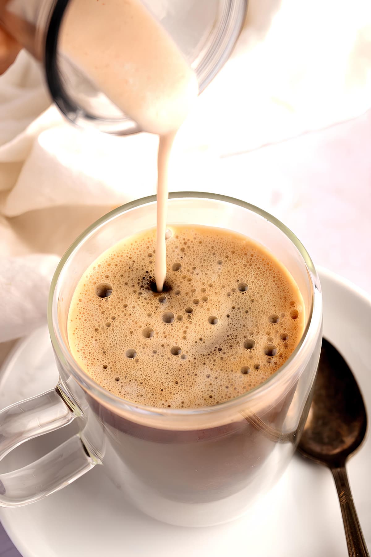 Homemade Coconut Coffee Creamer Recipe poured over black coffee on a glass mug. 