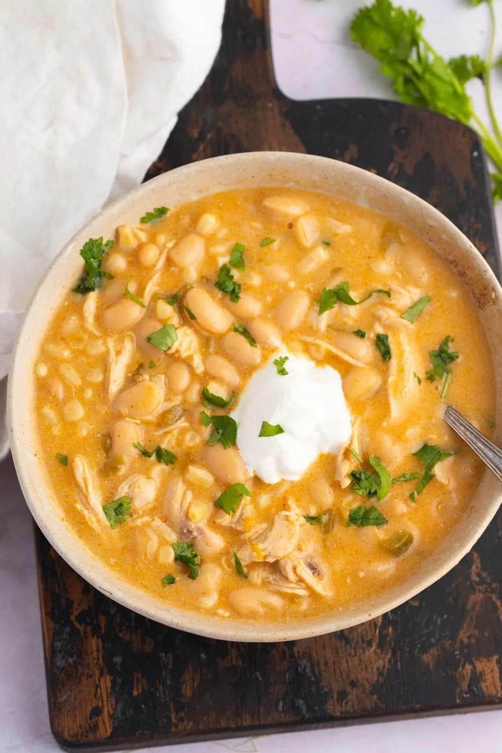 Bowl of Crockpot White Chicken Chili on a Wooden Board