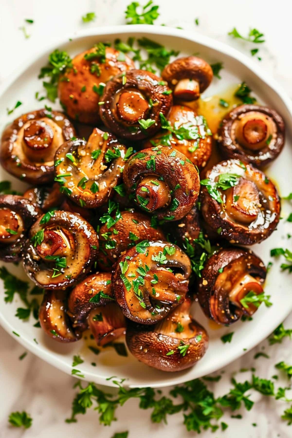 Garlic butter mushroom served on a plate garnished with chopped fresh parsley