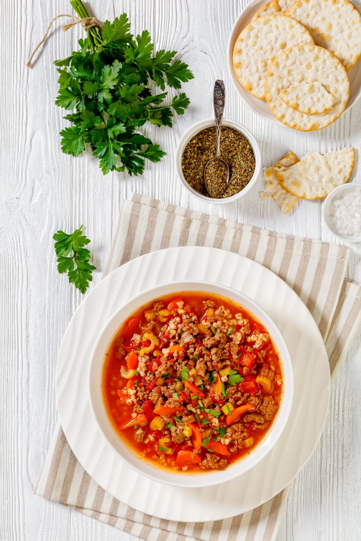 Hamburger soup served on a bowl with mix of veggies and ground meat. 