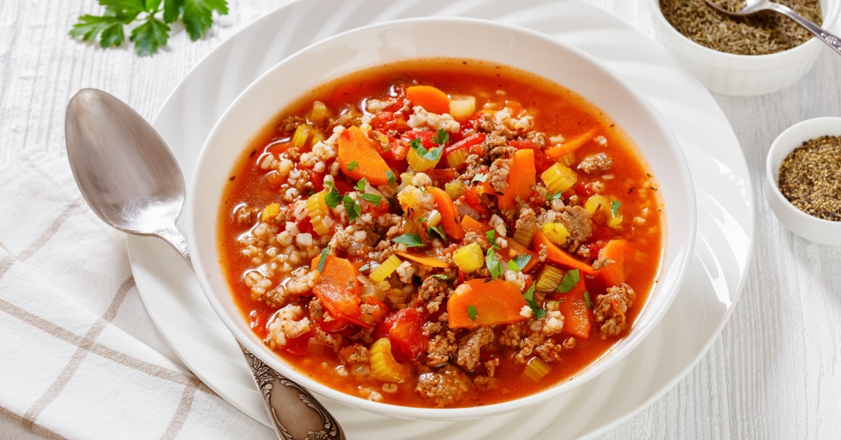 Hamburger soup in a white bowl with spoon.