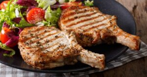 Homemade Grilled Porkchops with Vegetables in a Black Plate