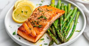Homemade salmon fillet and aspragus with lemon slices on a white plate