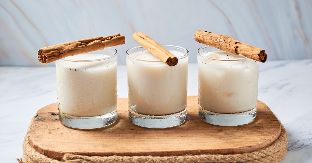 A wooden tray with three glasses of mexican horchata, perfectly arranged for a refreshing and wholesome beverage.