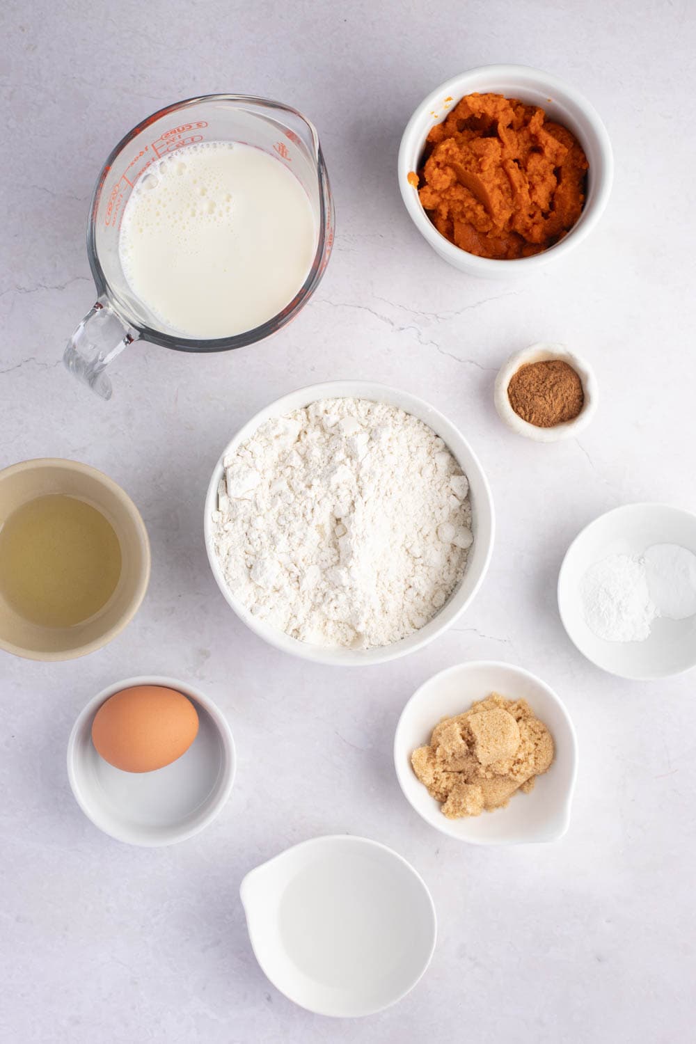 Ingredients for pumpkin pancakes including pumpkin puree, flour, brown sugar and milk