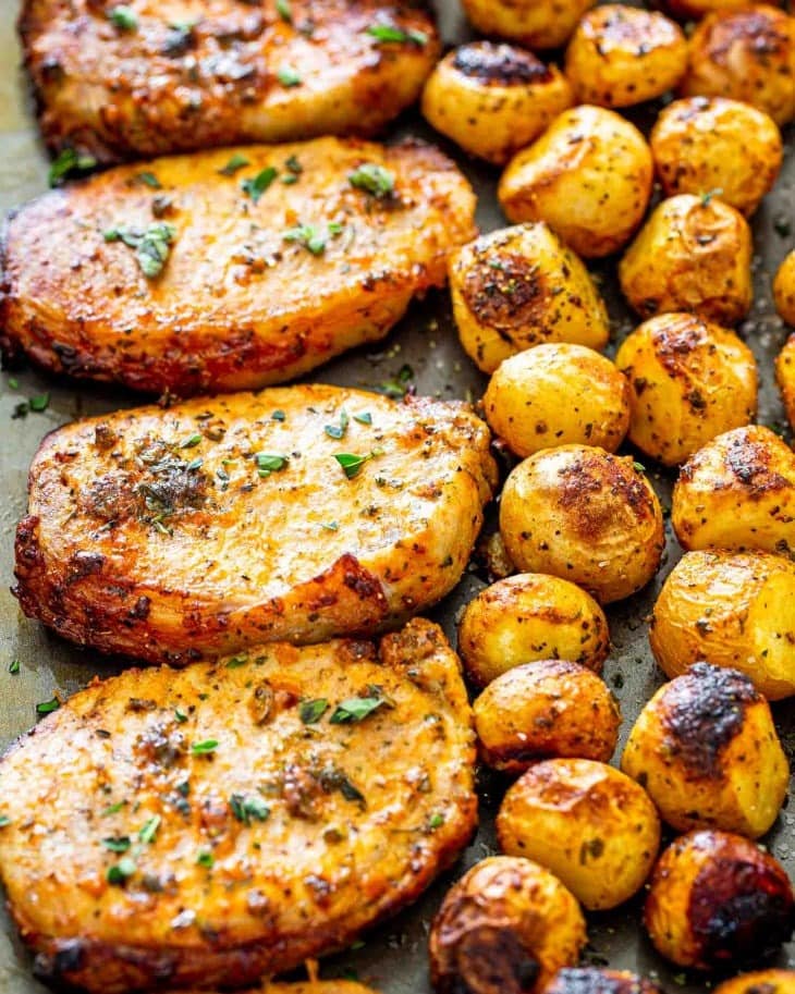 Seasoned pork chops and potatoes in pan. 