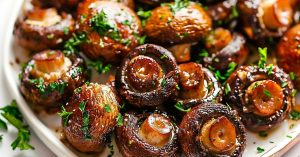 Sauteed garlic butter mushroom on a plate garnished with chopped parsley.