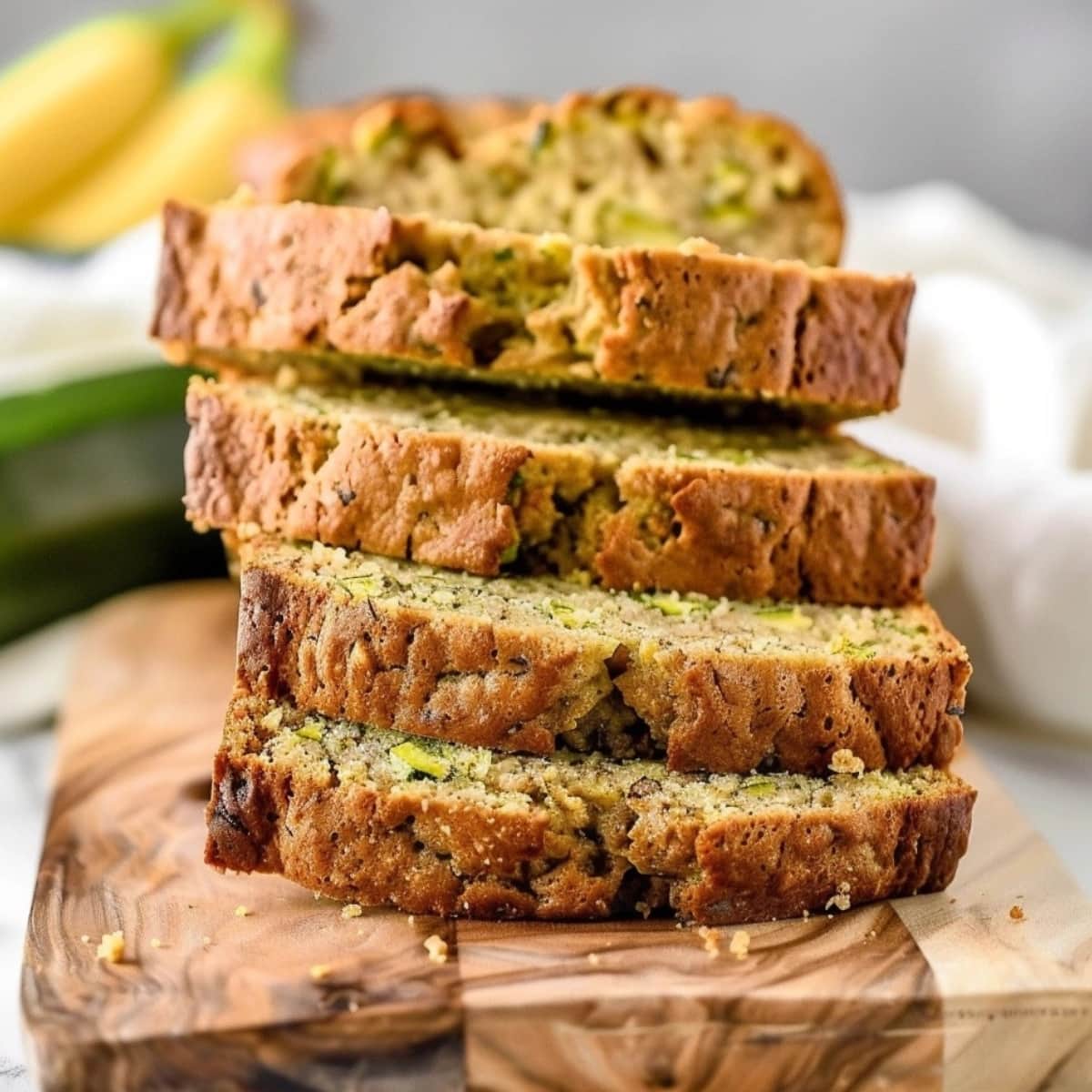 Sliced banana zucchini bread stack in a wooden board.