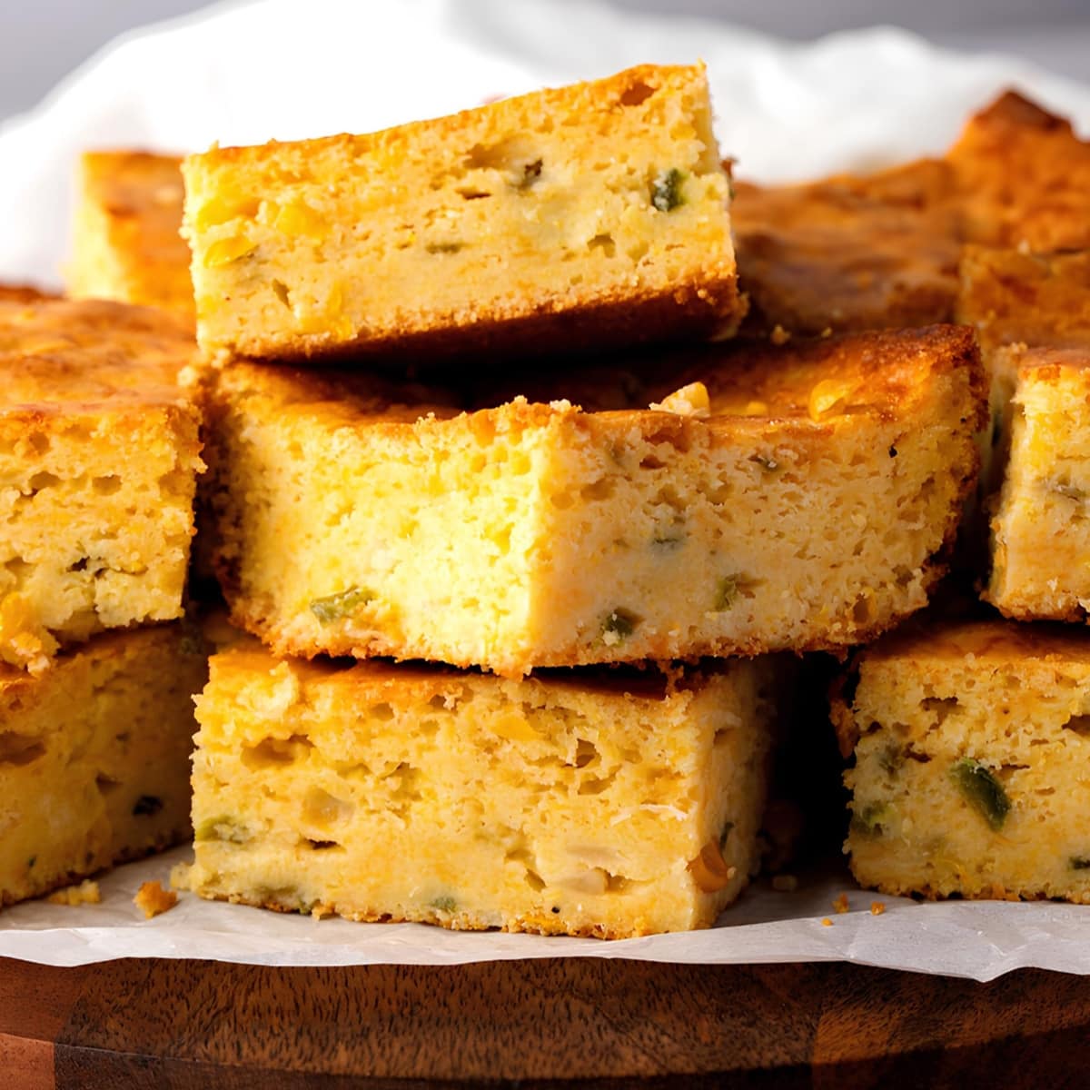 Closeup of stack of sliced Mexican cornbread on top of wooden board. 
