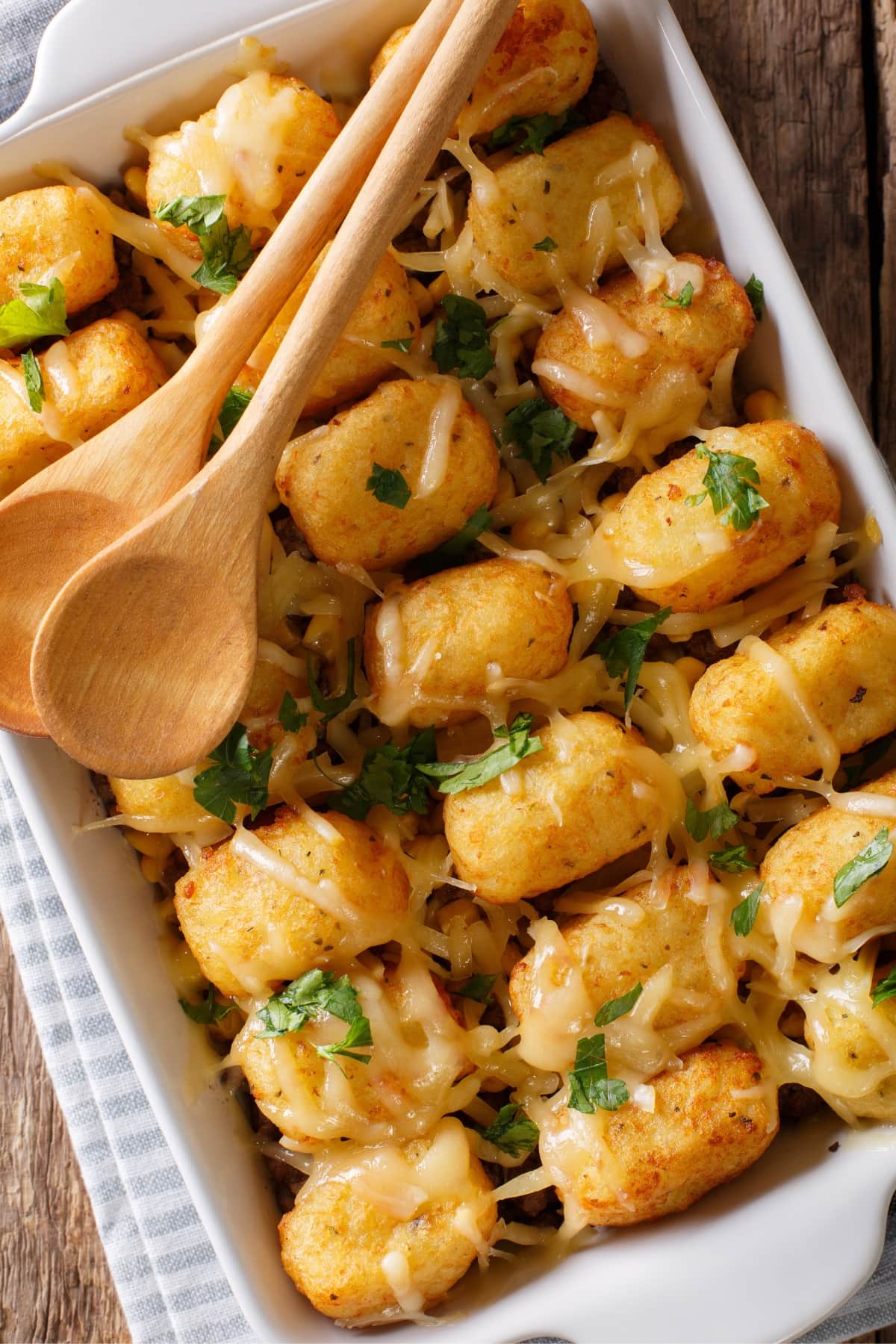 Tater tots casserole with two wooden spoon on top. 