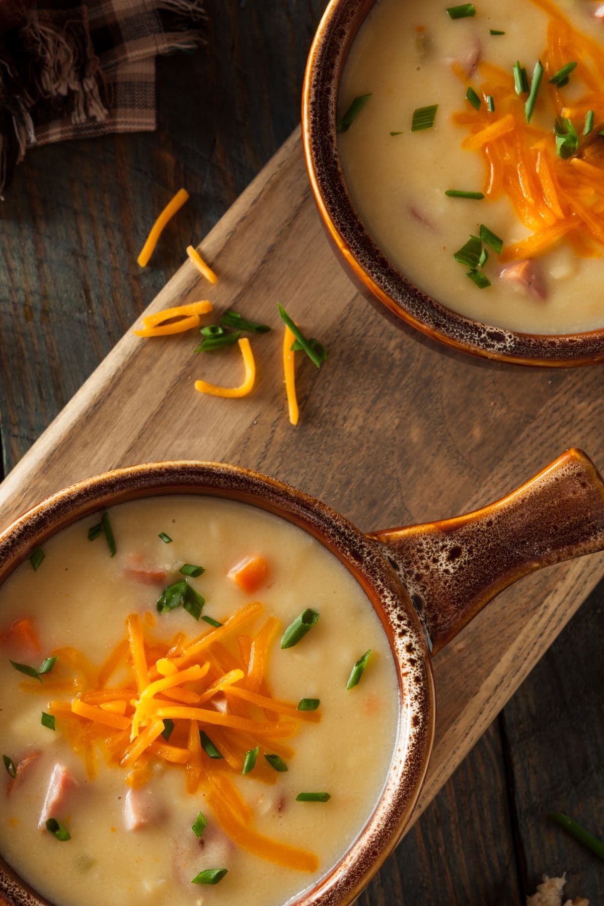 Top view of two pots with beer cheese soup garnished with grated cheese. 