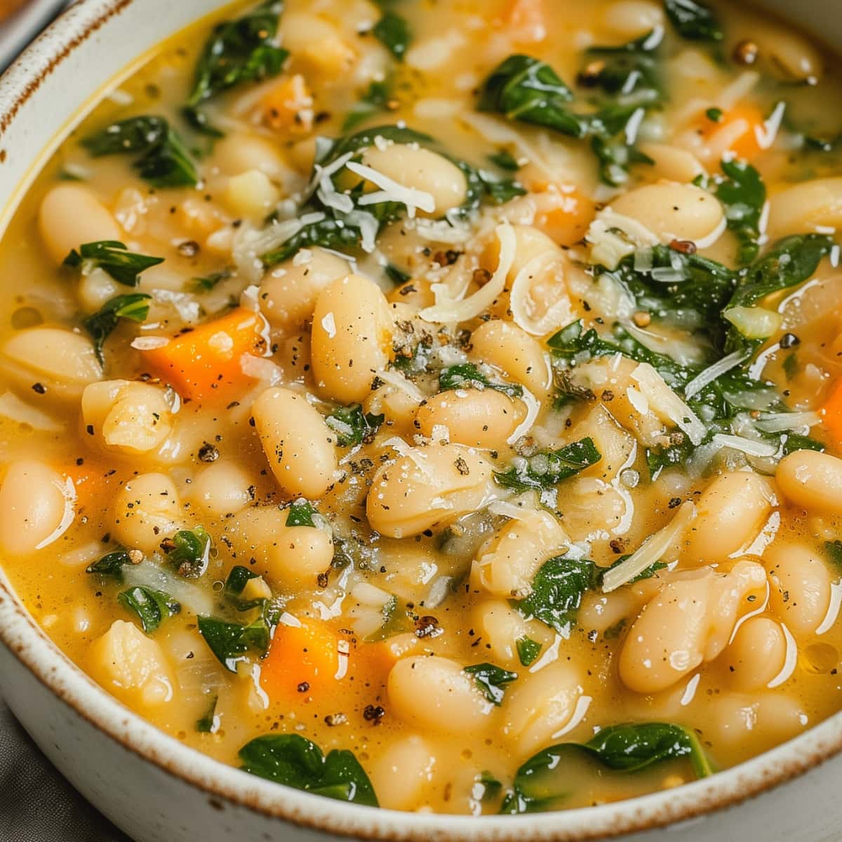 White bean soup in a bowl garnished with grated parmesan cheese.